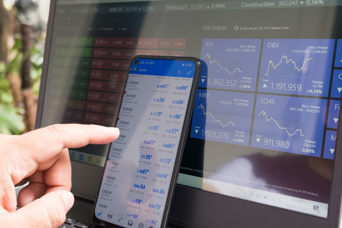 Live currency quotes on a phone beside a trading terminal